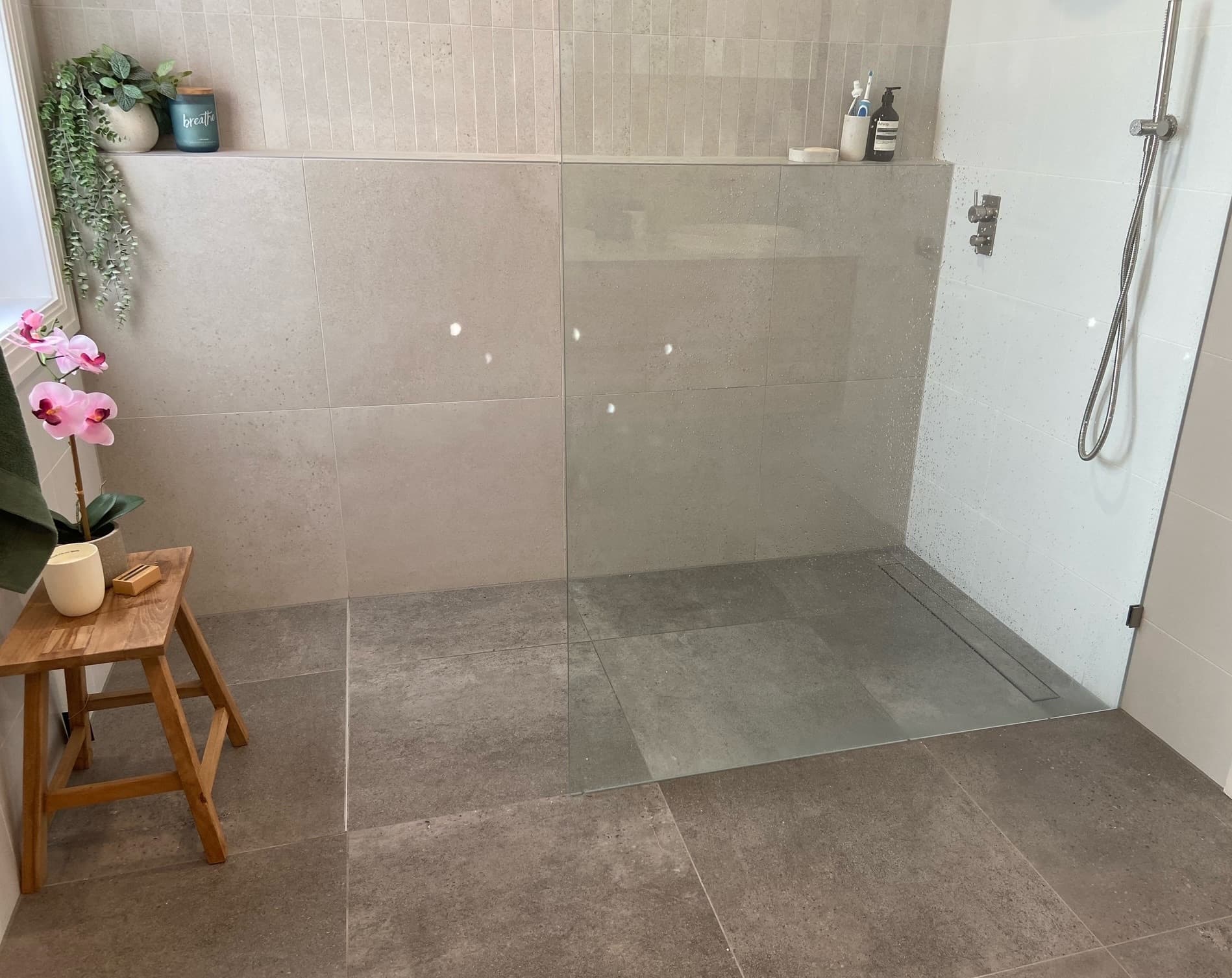 Modern bathroom with floor-to-ceiling tiles and glass-framed shower